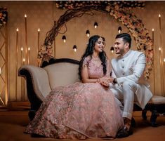 a man and woman sitting next to each other on a couch in front of candles