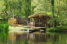 there is a small wooden cabin on the water's edge with two chairs in it