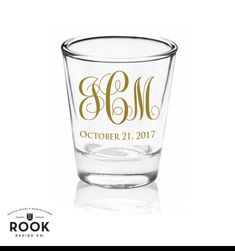 a shot glass with the initials and date engraved in gold on it, sitting on a white background