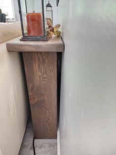 a candle is sitting on top of a wooden table next to a white couch and wall