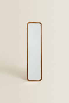 a wooden mirror sitting on top of a white wall