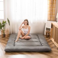 a woman sitting on top of a futon mattress