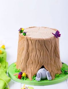 there is a cake that looks like a tree stump with an elephant on it and flowers around the base