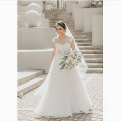 a woman in a wedding dress is walking down the stairs with her bouquet on her hand