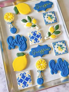 decorated cookies in the shape of lemons, blue and yellow on a baking sheet