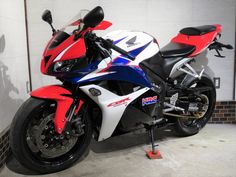 a red, white and blue motorcycle parked in a garage