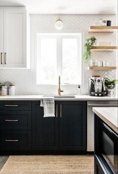 a kitchen with black cabinets and white counter tops is pictured in this image, there are plants on the shelves above the sink