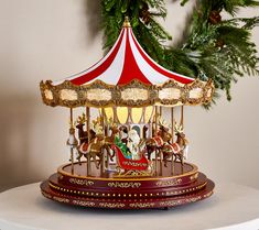 a merry go round carousel sitting on top of a table next to a christmas tree