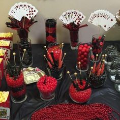 a table topped with lots of candy and vases filled with red candies next to each other