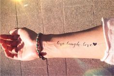 a person with a wrist tattoo that says live laugh love