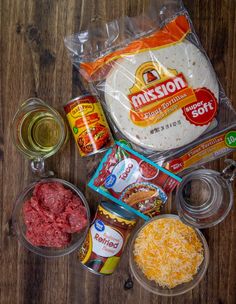 the ingredients to make an entree laid out on a wooden table, including ground beef, cheese, mustard, and seasonings