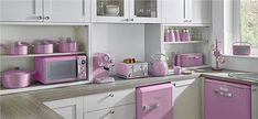 a kitchen with white cabinets and pink appliances