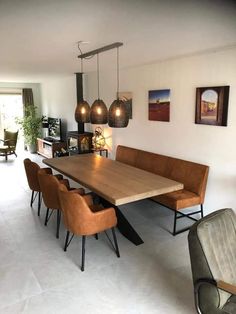 a dining room table and chairs with lights hanging from the ceiling