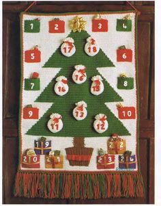 a cross stitch christmas tree hanging on a wall next to a clock and other decorations