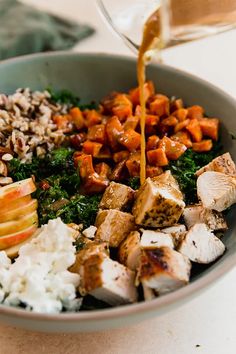 a bowl filled with rice, meat and vegetables being poured into it by a pitcher