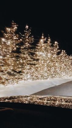 a man riding a snowboard down the side of a snow covered slope at night