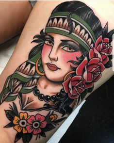 a woman's leg with tattoos on it and flowers in her hair is shown