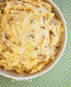 a white bowl filled with mashed potatoes on top of a blue and green tablecloth