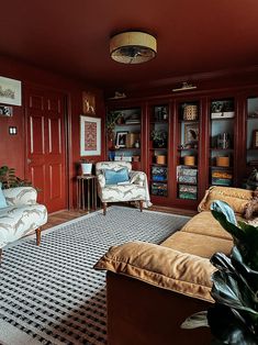 a living room with two couches and a rug in front of the bookshelves