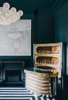 a living room with black walls and striped flooring, chandelier above the fireplace