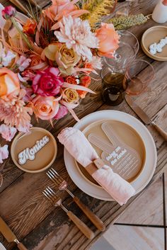 a wooden table topped with plates and flowers