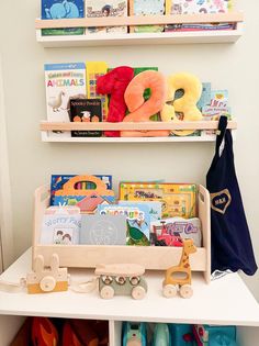 two shelves filled with books and toys on top of a white shelf in a child's room