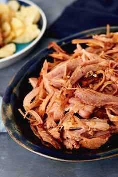 a plate full of sliced meat next to a bowl of potato wedges on a table