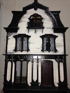 an old black and white doll house with windows