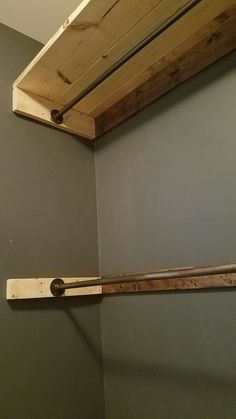 a baseball bat sitting on top of a wooden shelf next to a wall mounted toilet paper dispenser