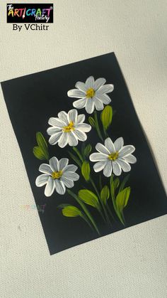 some white flowers are on a black and white paper with green leaves in the middle