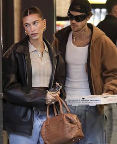 the man and woman are walking down the street with their handbags in each other's hands