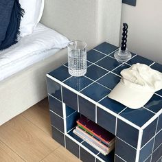 a blue tiled side table with a hat on top and a glass cup sitting next to it