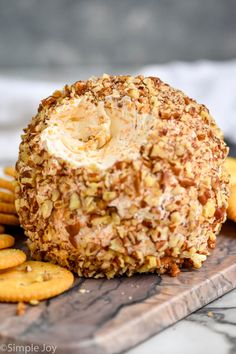 a cheese ball is on a wooden board surrounded by crackers