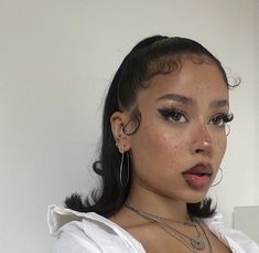 a woman with freckled hair and blue eyes is posing for the camera while wearing large hoop earrings