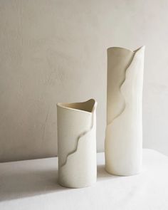 two white vases sitting next to each other on a table