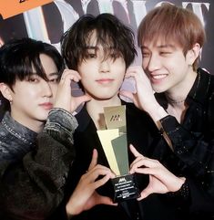 three young men are posing for the camera with an award in front of their faces