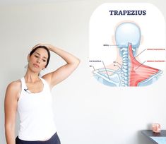 a woman standing in front of a wall with a diagram of the neck and shoulder