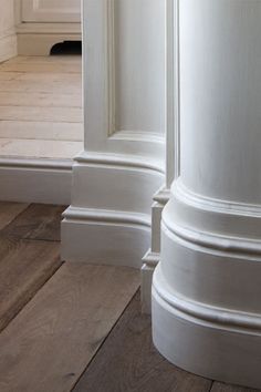 the corner of a room with white walls and wood floors