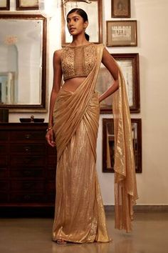 Gold pre-draped saree with all over metallic shimmery finish. Paired with sleeveless boat neck padded blouse with tonal nalki, beads, sequin floral bloom jaal embroidery.
Components: 2
Pattern: Embroidery
Type Of Work: Tonal Beads, Sequin, Nalki
Neckline: Boat Neck
Sleeve Type: Sleeveless
Fabric: Viscose Flat Chiffon Lurex , Lining: Shantoon
Color: Gold
Other Details: 
Attached inner lining
Padded blouse
Weight: 0.5kgs
Length: 42inches
Model Height: 5ft 10inches, wearing size XS
Note: The outfit Jaal Embroidery, Sangeet Outfit, Draped Saree, Peach Saree, Saree Wearing, Saree Wearing Styles, Gown Pictures, Saree Gown, Padded Blouse