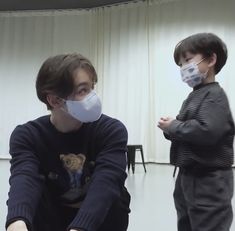 two young boys wearing face masks while sitting on the floor