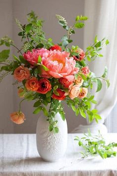 a white vase filled with lots of flowers on top of a table