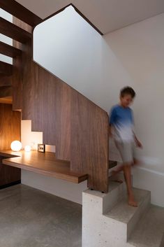 a young boy is walking up the stairs in this modern home with wood and white decor