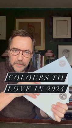 a man holding up a sign that says colours to love in 2021