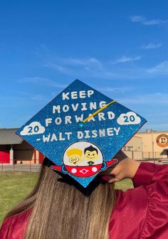 a woman wearing a blue graduation cap with the words keep moving forward and walt disney on it