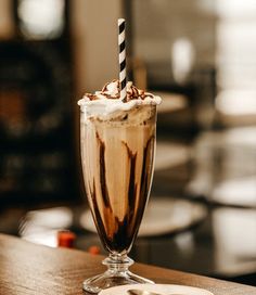 a chocolate milkshake with whipped cream in a tall glass on a wooden table