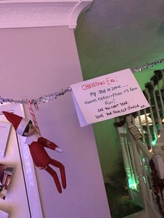 the elf is hanging on the wall next to the christmas tree with his name written on it