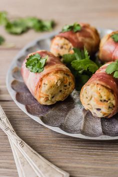 some food is wrapped in bacon and garnished with cilantro on a plate