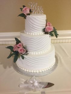 a three tiered white wedding cake with pink flowers