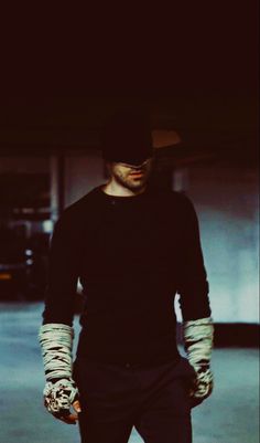 a man in black shirt and white gloves holding a skateboard