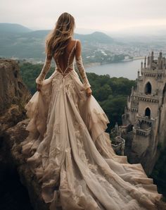 a woman standing on top of a cliff next to a castle